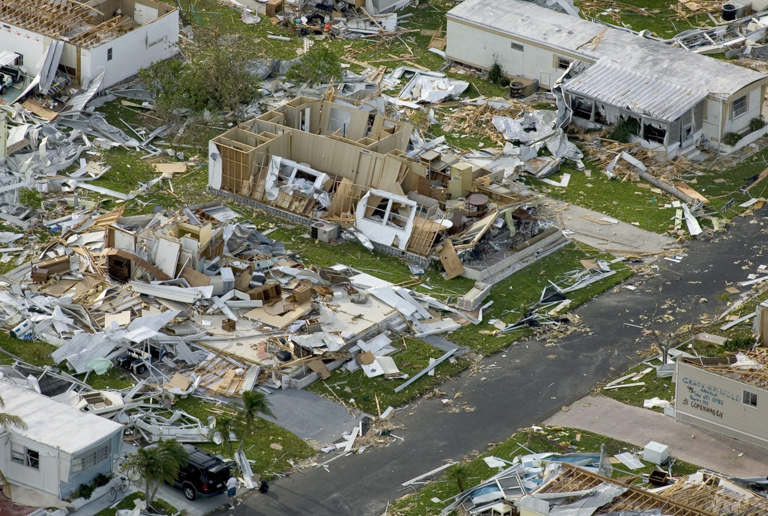 Florida homes strewn with debris, including fallen branches, broken furniture, and scattered belongings post hurricane.